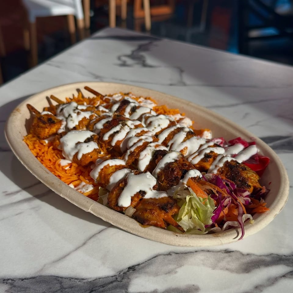 Mr.Cone Shawarma's chicken skewers with rice, salad, and white sauce in a biodegradable bowl.