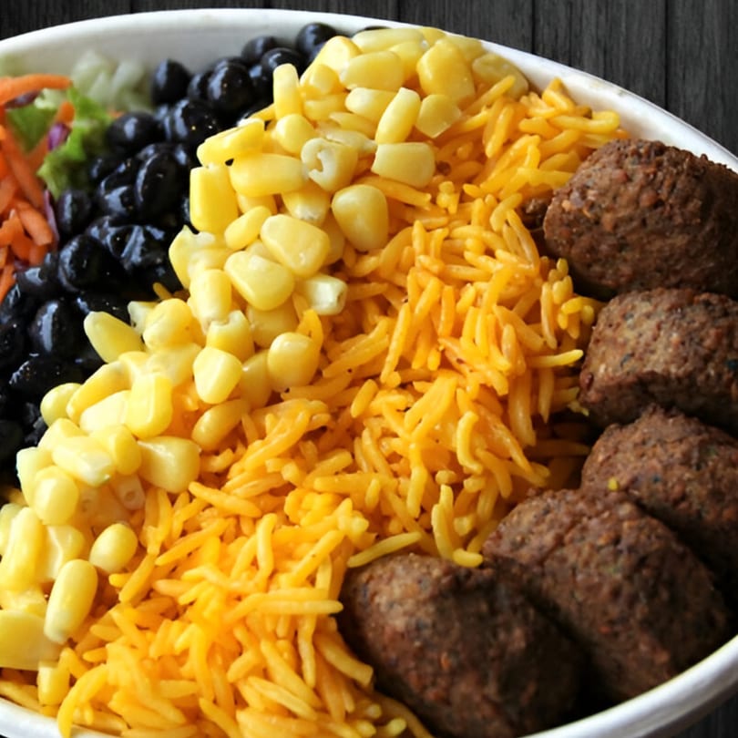 A Mr.Cone Shawarma bowl with falafel, yellow rice, corn, black beans, and shredded carrots.
